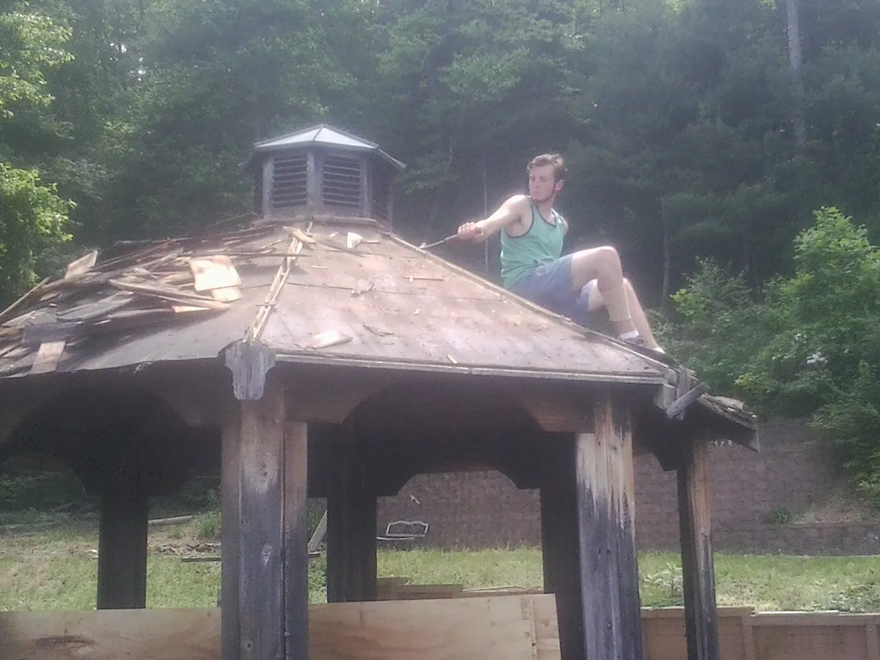 Tearing the old roof off a wooden gazebo before new shakes in Goodells