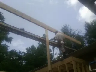 Carpenter setting a ridge beam over a new addition frame — Ice Dam Removal by Roofing Brothers in Goodells
