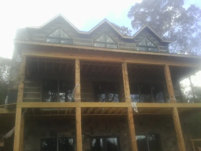 Dormers and porch framing on a large log home under construction — Roof Coating work by our crew in Goodells