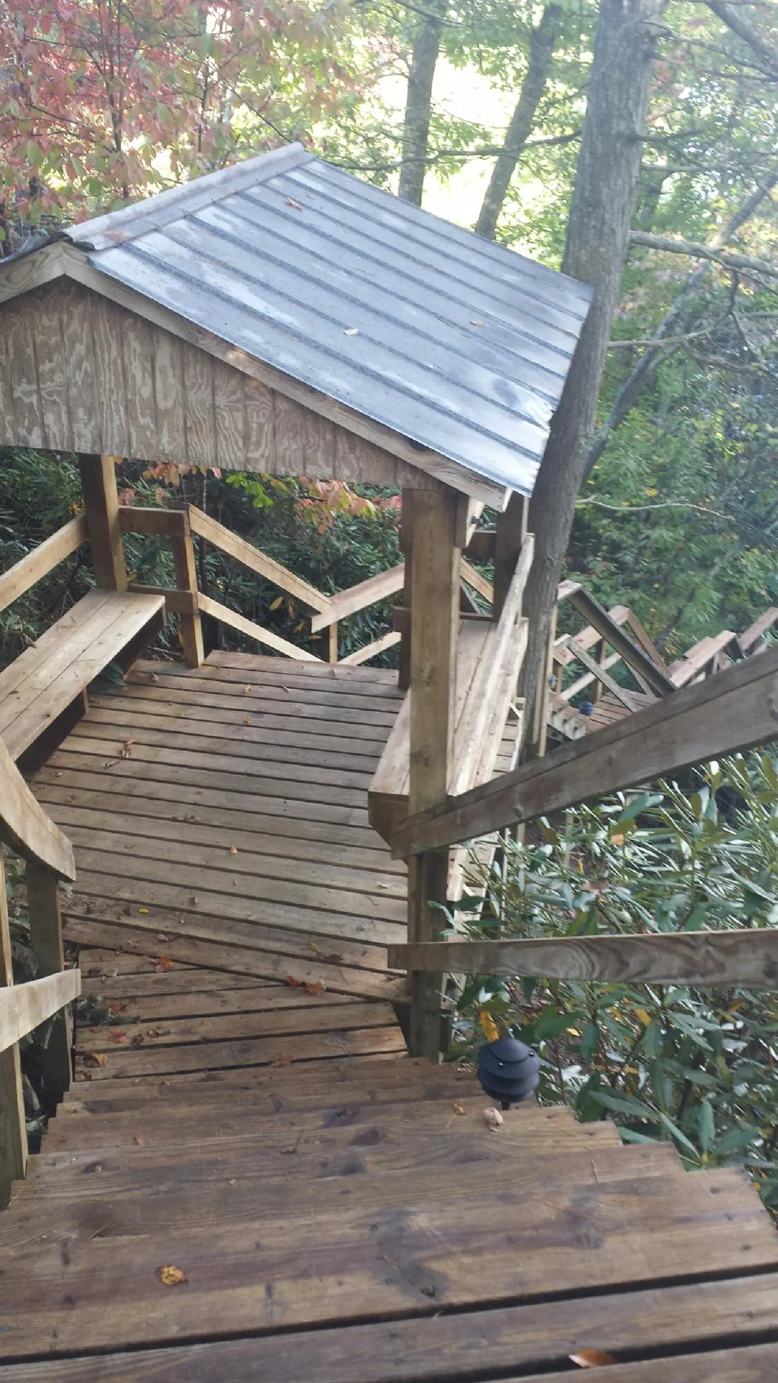 Metal roofed shelter over wooden steps on a wooded walkway — Skylight Repair & Installation work by our crew in Goodells