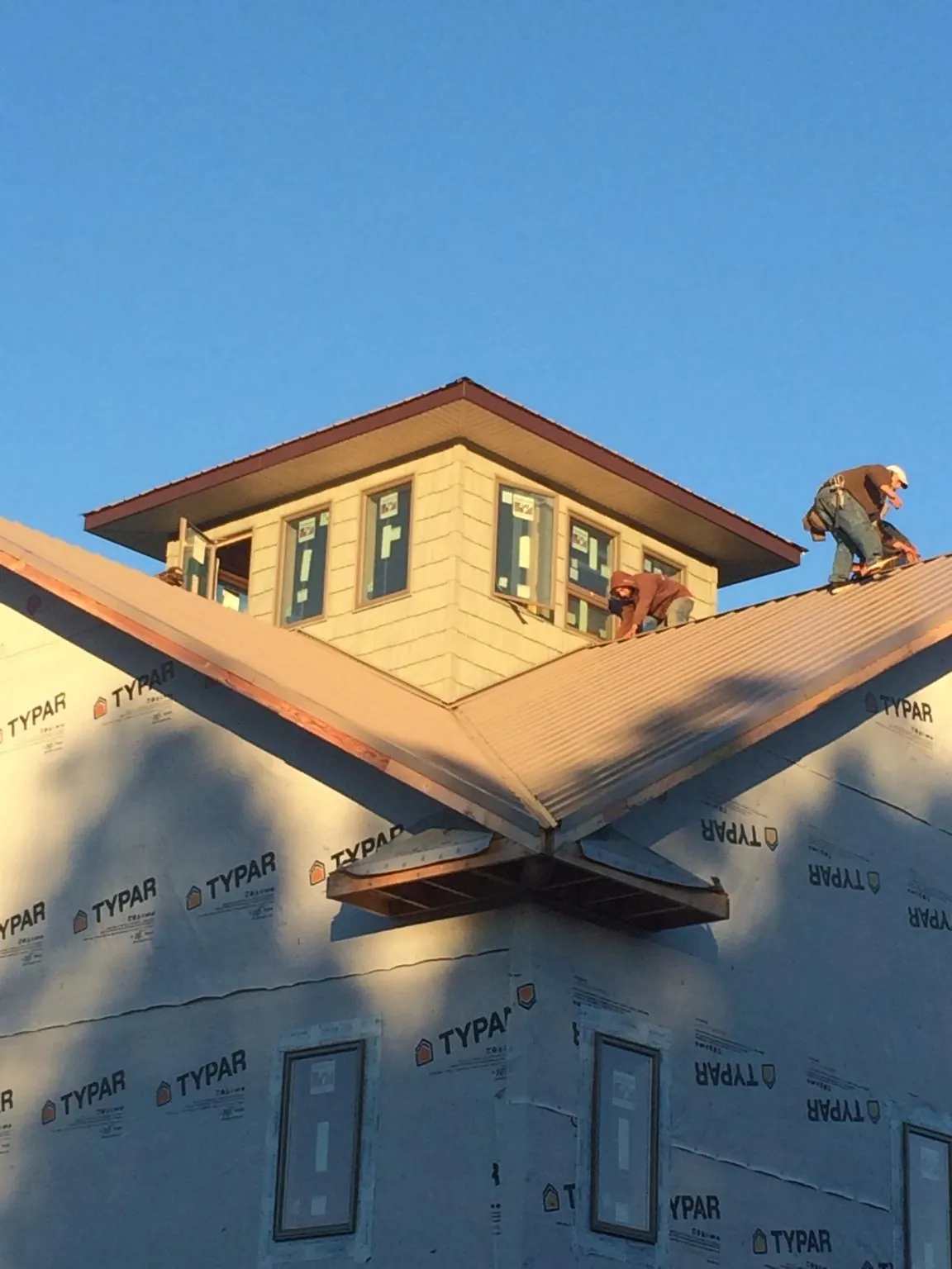 Roofers working around a rooftop cupola on a new metal roof at sunset — Roof Waterproofing in Goodells by Roofing Brothers
